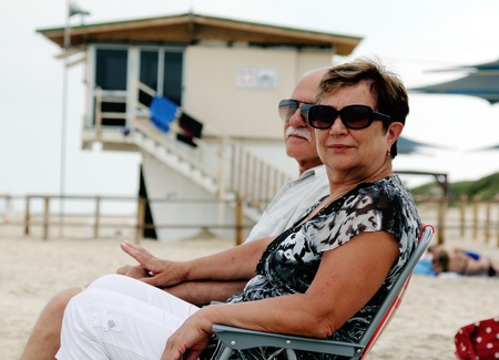 Portrait of happy senior couple sitting together on a beachの写真素材
