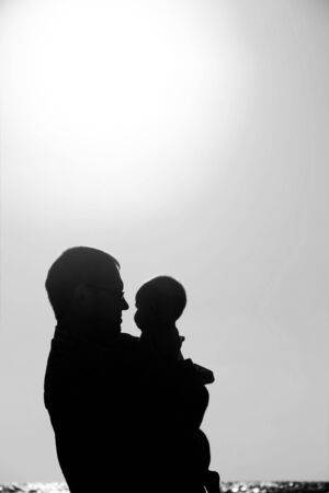 Dad and child on the beach at sunsetの写真素材