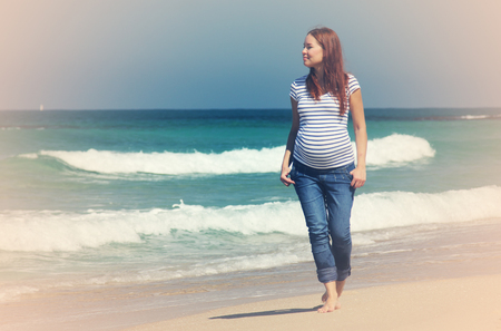 Young pregnant woman walking at the beachの写真素材