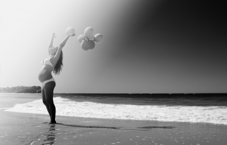Young pregnant woman holding red balloonsの写真素材
