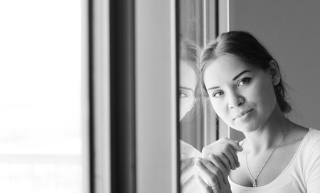 beautiful woman stands in front of the windowの写真素材