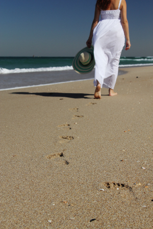 Young woman in white dress walking at the beach  Focus on the sand の写真素材