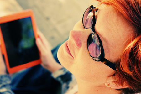 Redhead woman with tablet outdoors