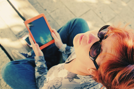 Redhead woman with tablet outdoorsの写真素材