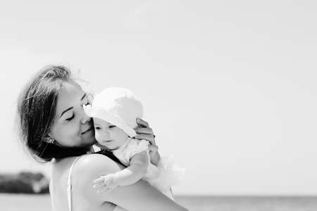 Portrait of happy loving mother and her baby at the beachの写真素材
