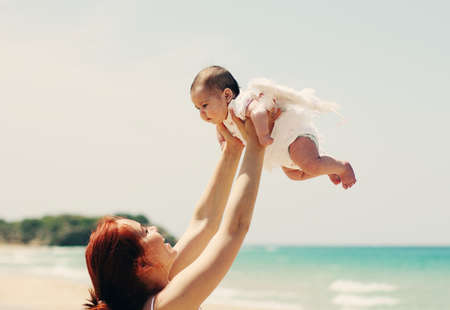 Portrait of happy loving mother and her baby at the beachの写真素材