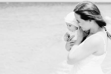 Portrait of happy loving mother and her baby at the beachの写真素材