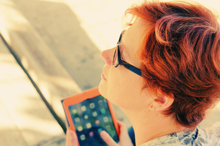 Redhead woman with tablet outdoorsの写真素材