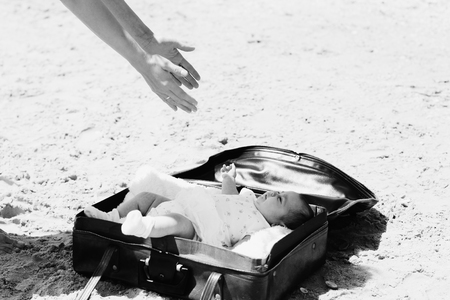 cute 2-month old baby lying in vintage case on the beachの写真素材