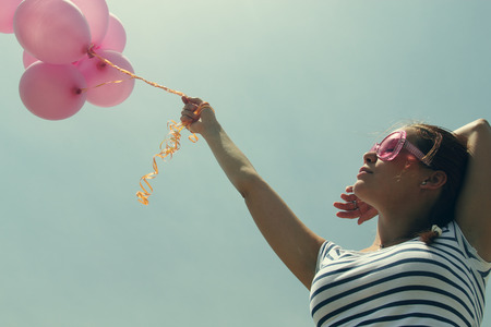 beautiful woman with colorful balloons outsideの写真素材