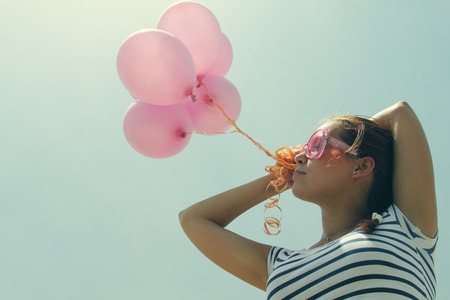 beautiful woman with colorful balloons outsideの写真素材