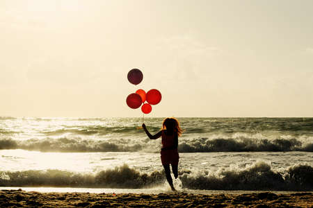 beautiful woman with colorful balloons on seasideの写真素材