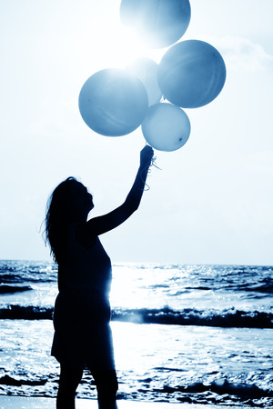 beautiful woman with colorful balloons on seasideの写真素材
