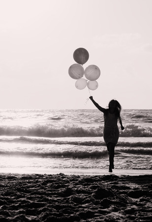beautiful woman with colorful balloons on seasideの写真素材