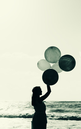 beautiful woman with colorful balloons on seasideの写真素材