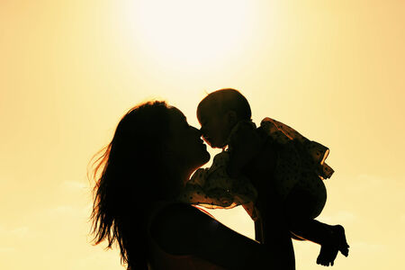 Silhouette of mother and baby at sunsetの写真素材