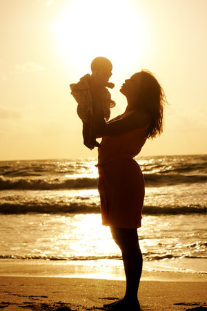 Silhouette of mother and baby at sunsetの写真素材