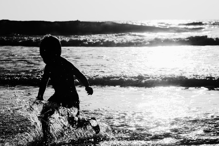happy kid playing on the beach at sunsetの写真素材