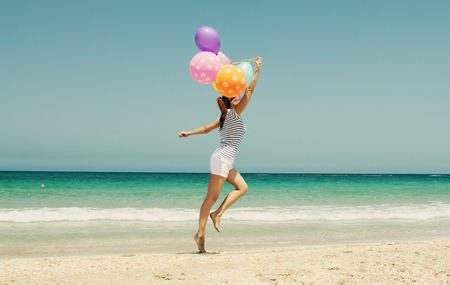 beautiful woman with colorful balloons on seasideの写真素材