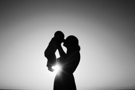 Silhouette of mother and baby at sunsetの写真素材