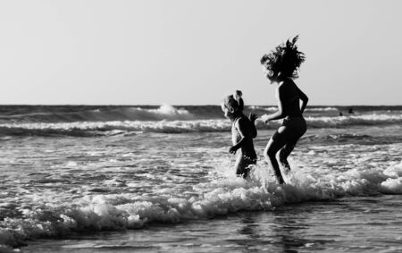 two happy kids playing on the beach at sunsetの写真素材