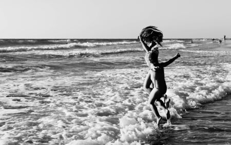two happy kids playing on the beach at sunsetの写真素材