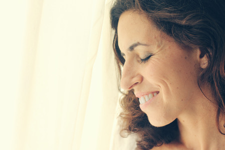 beautiful 35 year old woman stands near the windowの写真素材