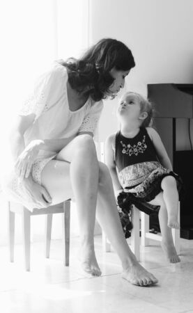 beautiful mother and daughter sitting near the windowの写真素材