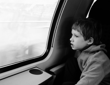 Cute 6 years old boy looking through the window