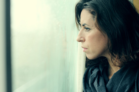 beautiful 35 year old woman stands in front of the windowの写真素材
