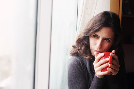 Beautiful young woman holding cup of coffeeの写真素材