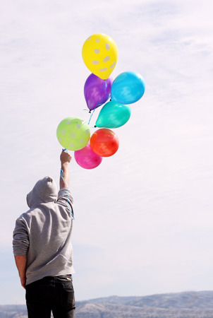 Man holding colorful balloons outsideの写真素材