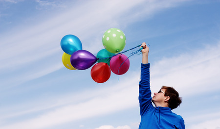 woman holding colorful balloons outsideの写真素材