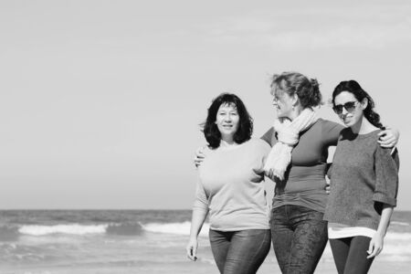 Three best friends walking at seasideの写真素材
