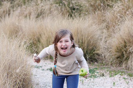 portrait of a beautiful happy girl eating green appleの写真素材