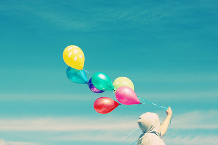 Man holding colorful balloons outsideの写真素材