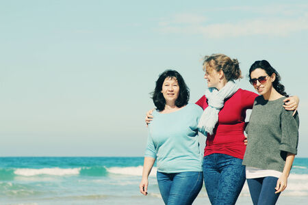 Three best friends walking at seasideの写真素材