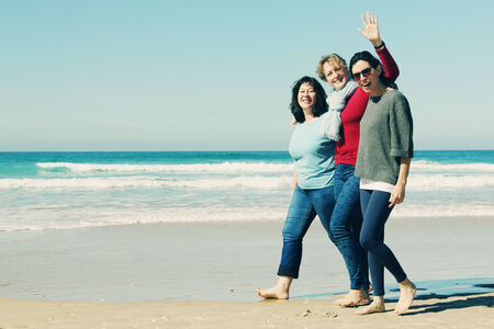 Three best friends walking at seasideの写真素材