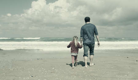 father and daughter walking on the beachの写真素材