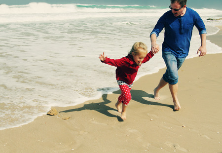 father and daughter walking on the beachの写真素材