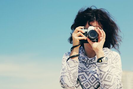 Woman with vintage retro camera having fun on the beach on blue sea backgroundの写真素材