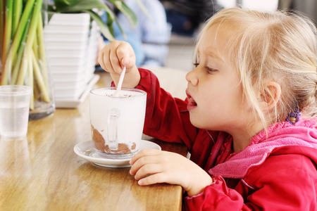 Adorable 4 years old girl sitting in cafeの写真素材