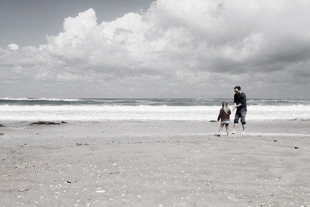 father and daughter walking on the beachの写真素材