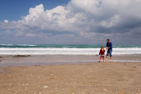 father and daughter walking on the beachの写真素材