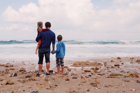 father, son and daughter walking on the beachの写真素材