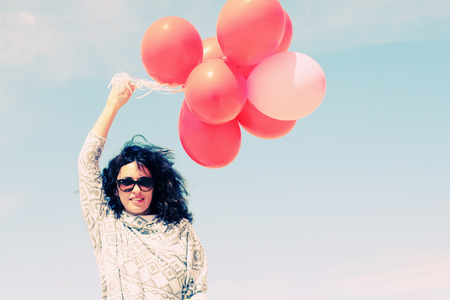 beautiful woman holding red balloonsの写真素材