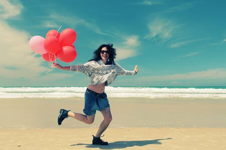 beautiful woman holding red balloonsの写真素材