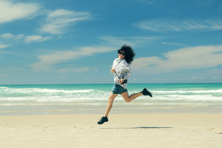 Woman with vintage retro camera having fun on the beach on blue sea backgroundの写真素材