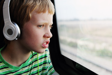 Portrait of cute boy with headphones traveling in the trainの写真素材