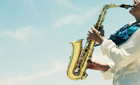 Saxophonist playing on saxophone on blue sky backgroundの写真素材